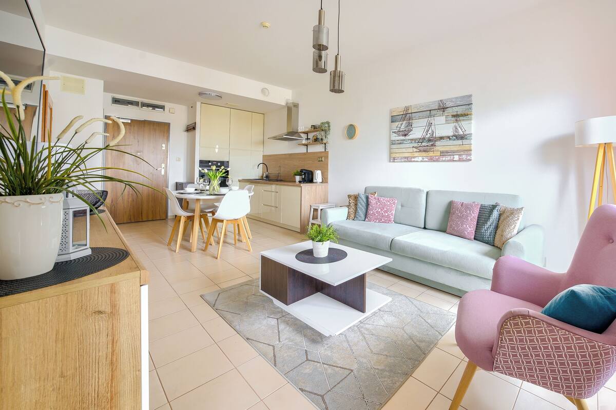 Ein modernes Wohnzimmer mit einer Couch, einem Esstisch und einer Küche im Hintergrund.