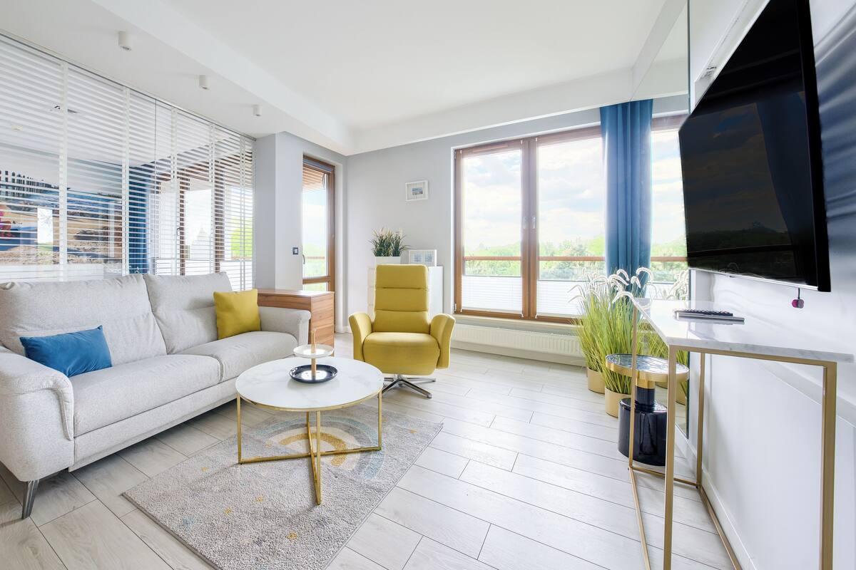 Ein modernes Wohnzimmer mit Sofa, Sessel, Couchtisch und Fernseher.