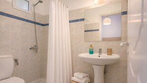A bathroom with a shower, toilet, sink, and a small stool. - Nel Mare Studios (Zakynthos)