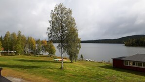Une vue sur le lac, avec une zone herbeuse, une balançoire et un petit bâtiment situé près de l’eau.
