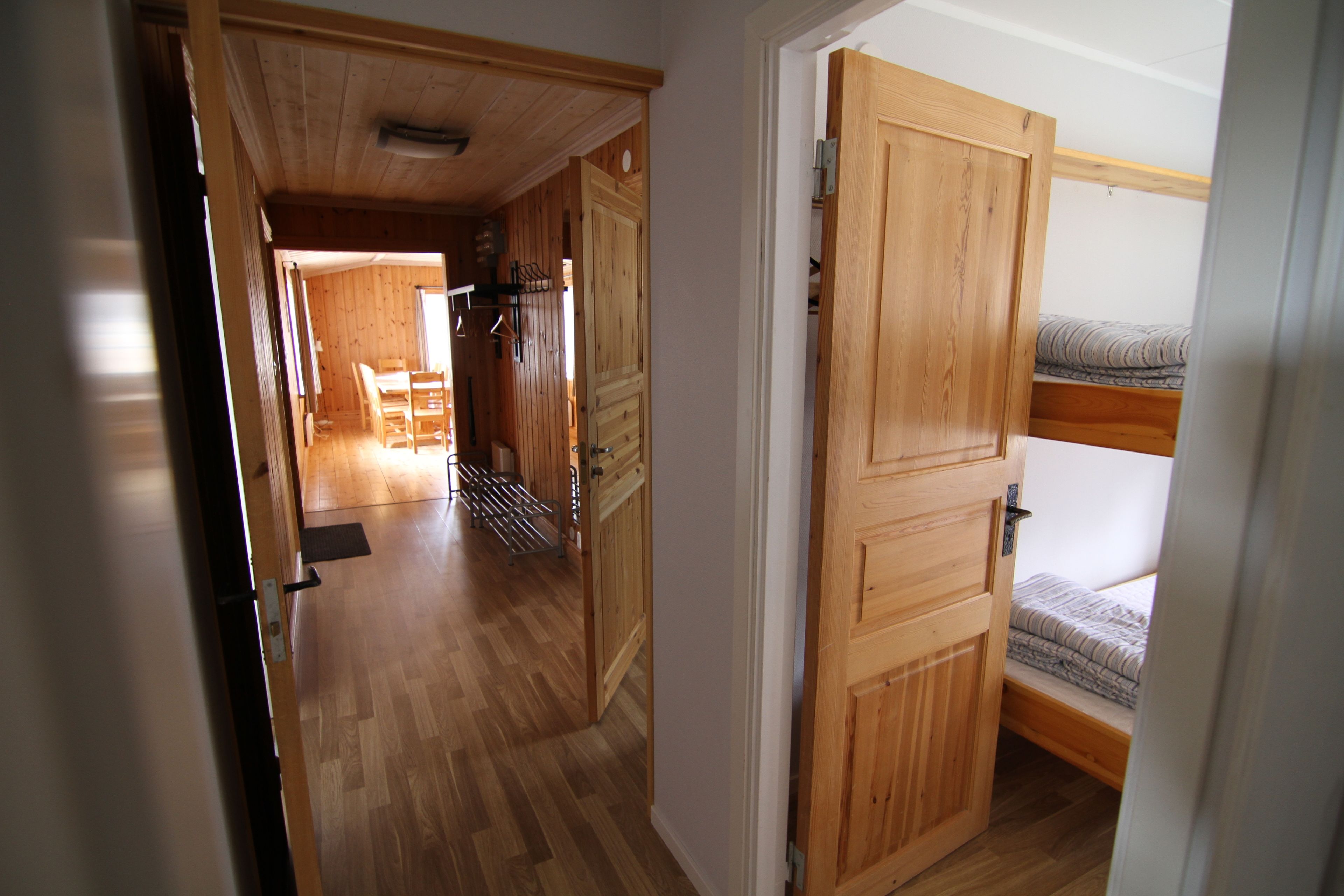 Un interior de madera con literas, un comedor con sillas y una cocina con lavamanos y encimera.