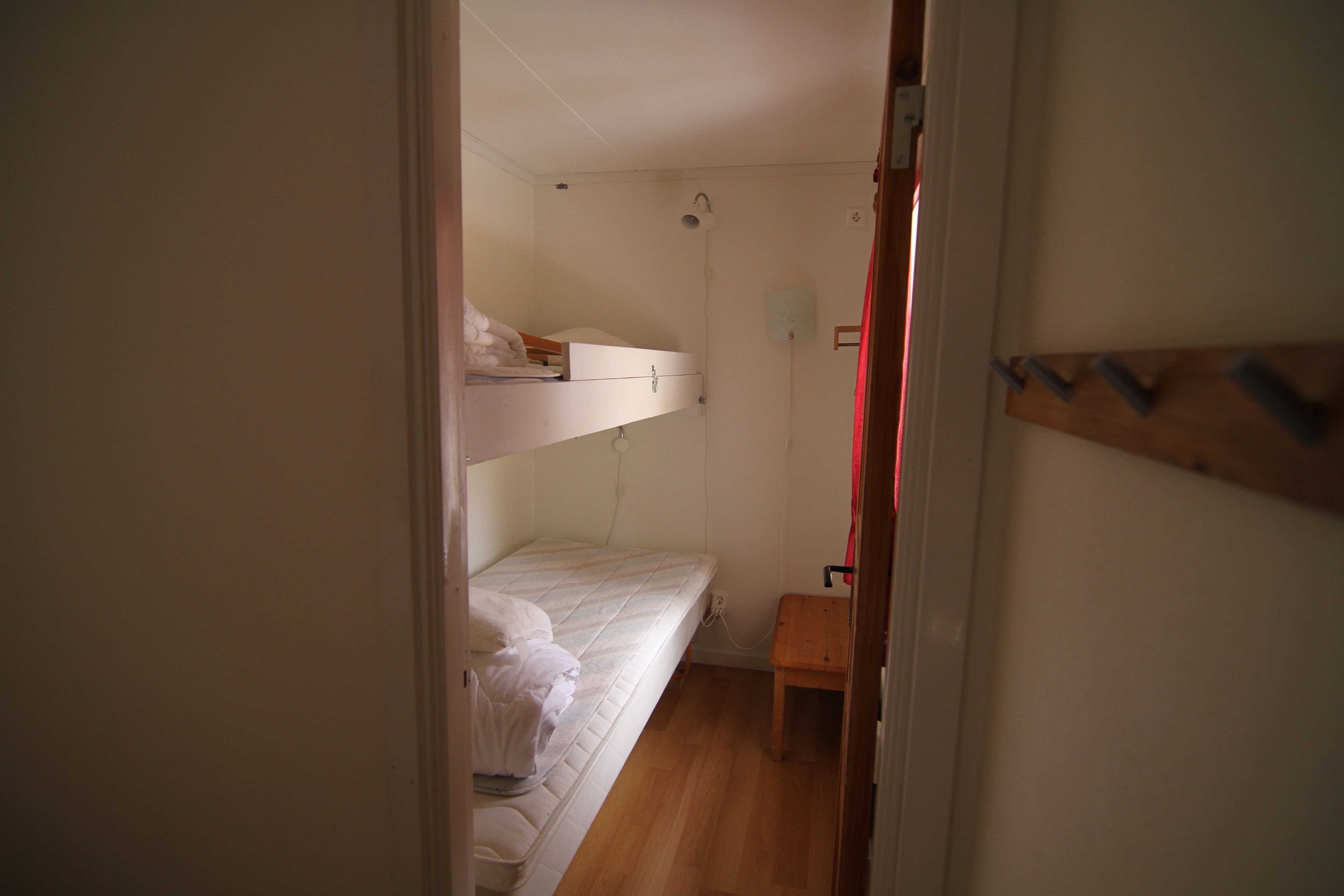 Una habitación pequeña y funcional con literas y un banco de madera.