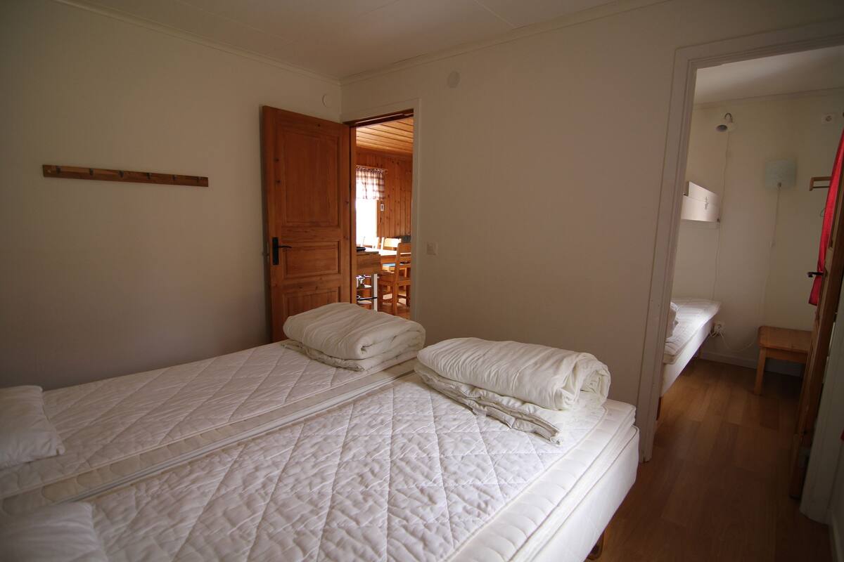 A bedroom with two single beds, a wooden door, and a small wooden bench.