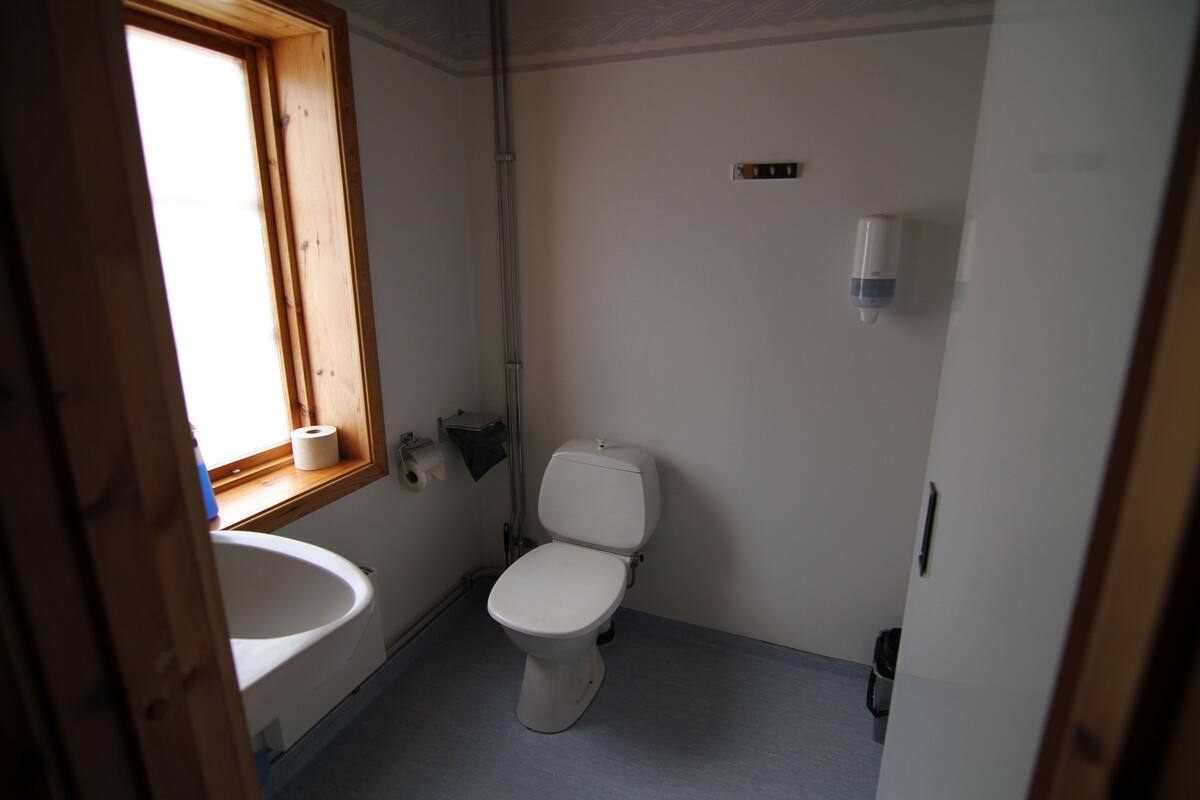 A small, clean bathroom with a toilet, sink, and window.