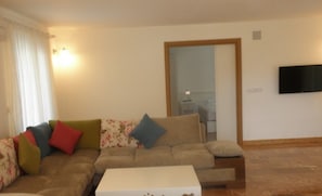 A living room with a sofa, a coffee table, a flat-screen TV mounted on the wall, and a door leading to another room. - Arikanda Hotel 2 (Kumluca)