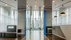 Un interior moderno con un separador de vidrio central, suelo de madera y una zona de cocina visible al otro lado.