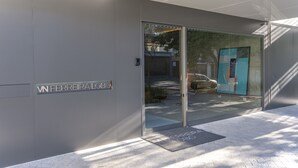 Een moderne gevel met een glazen deur en een metalen bord met de tekst 