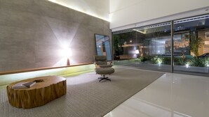 Een modern interieur met een groot raam, een houten bankje en een eigentijdse stoel.