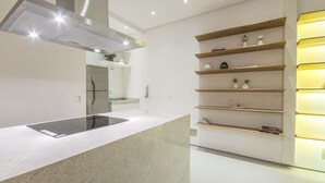 Een moderne keuken met een centraal eiland, inbouwplanken en inbouwspots.