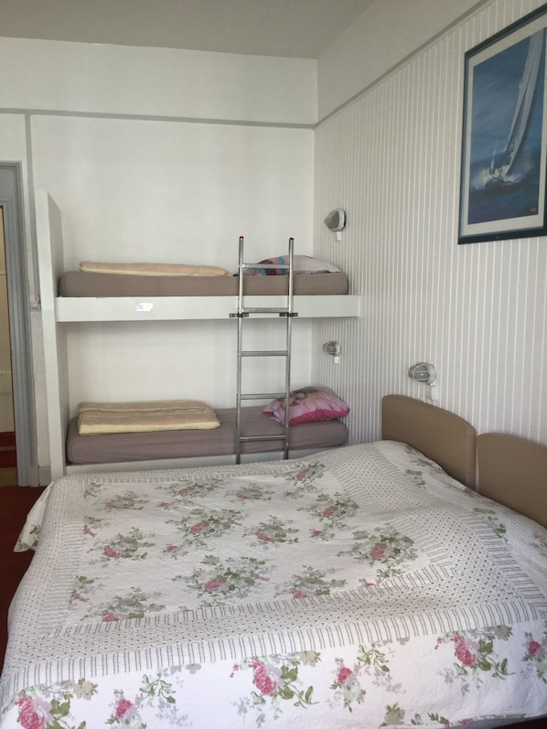A bunk bed room with a ladder, a framed picture on the wall, and a floral-patterned bedspread. - Auberge Riva Bella - Hostel (Le Touquet-Paris-Plage)