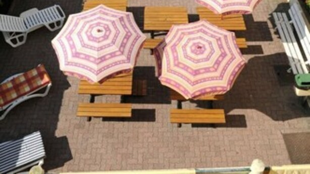 A courtyard with outdoor seating and umbrellas. - Auberge Riva Bella - Hostel (Le Touquet-Paris-Plage)