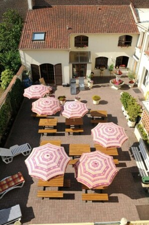A courtyard with outdoor seating and umbrellas. - Auberge Riva Bella - Hostel (Le Touquet-Paris-Plage)