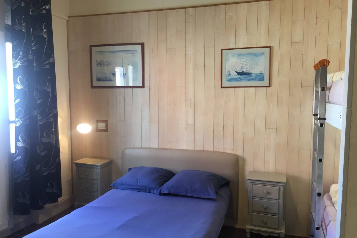 Een slaapkamer met een bed, twee nachtkastjes, een dressoir en twee ingelijste foto's aan de muur.