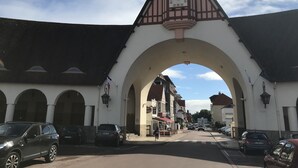 Eine Straße mit einem markanten Bogen, einem Glockenturm und geparkten Autos.