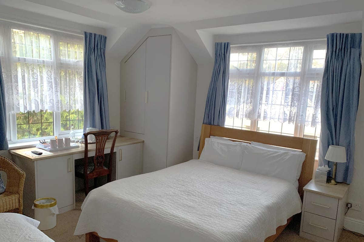 A bedroom with a bed, a desk, a chair, a wardrobe, and a nightstand.