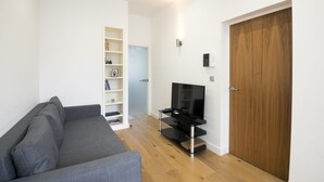 Un salon moderne avec un canapé gris, une porte en bois et une étagère intégrée pour la télévision.