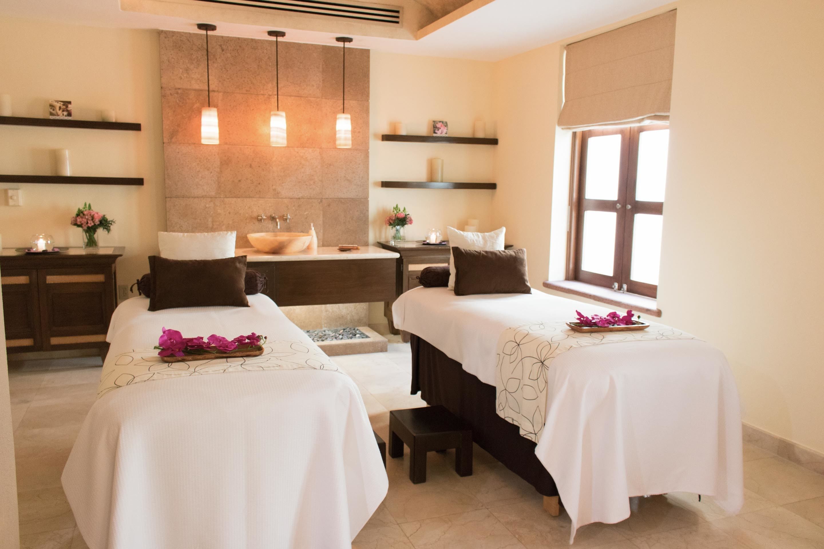 A hotel room with two beds, a bathroom, and a large window.