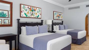 A hotel room with two beds, a desk, and artwork on the walls.
