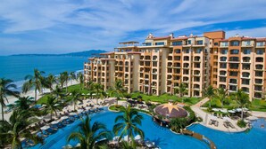 Un resort con una piscina grande, varios balcones y vista al océano.