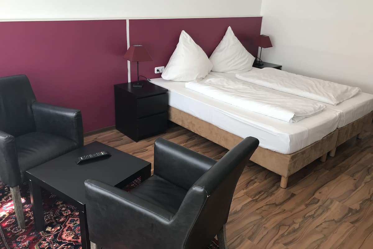 A hotel room with a bed, a nightstand, a desk, and two chairs.