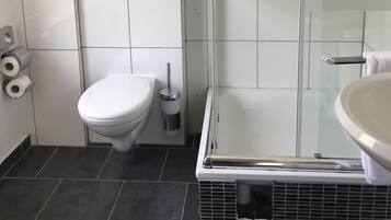 Ein modernes Badezimmer mit Toilette, Bidet und Duschkabine.
