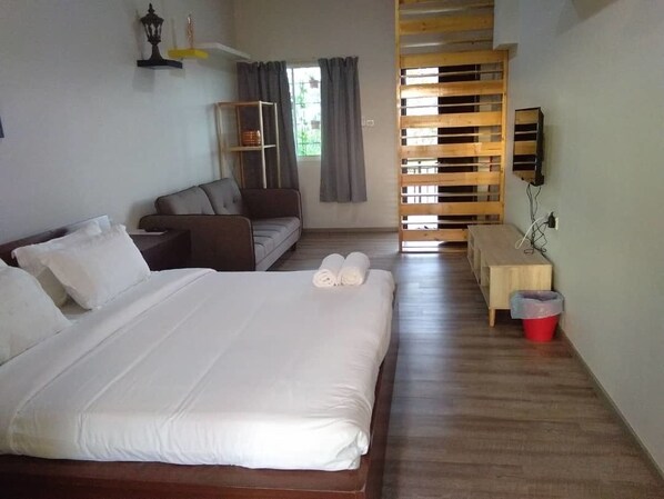 A hotel room with a large bed, a sofa, a small table, a TV, and a window with curtains. - Kokol Heights Villa (Kota Kinabalu)