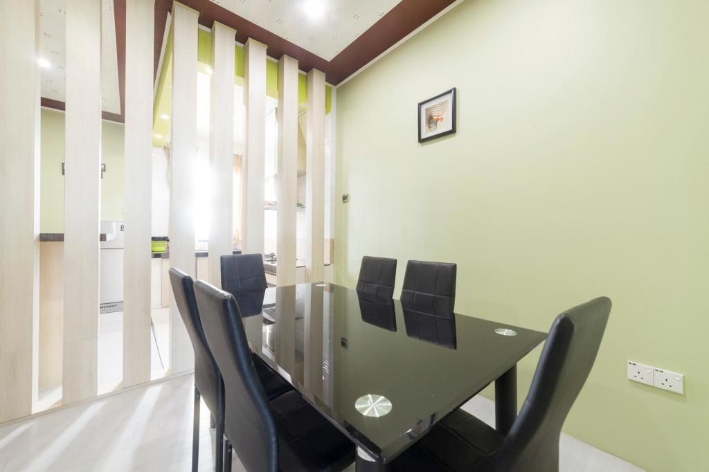 A conference room with a glass table, black chairs, and a green wall.