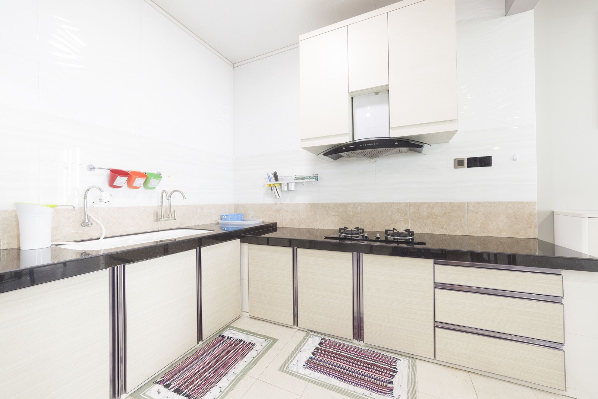 A modern kitchen with a black countertop, white cabinets, a stainless steel sink, and a gas stove.