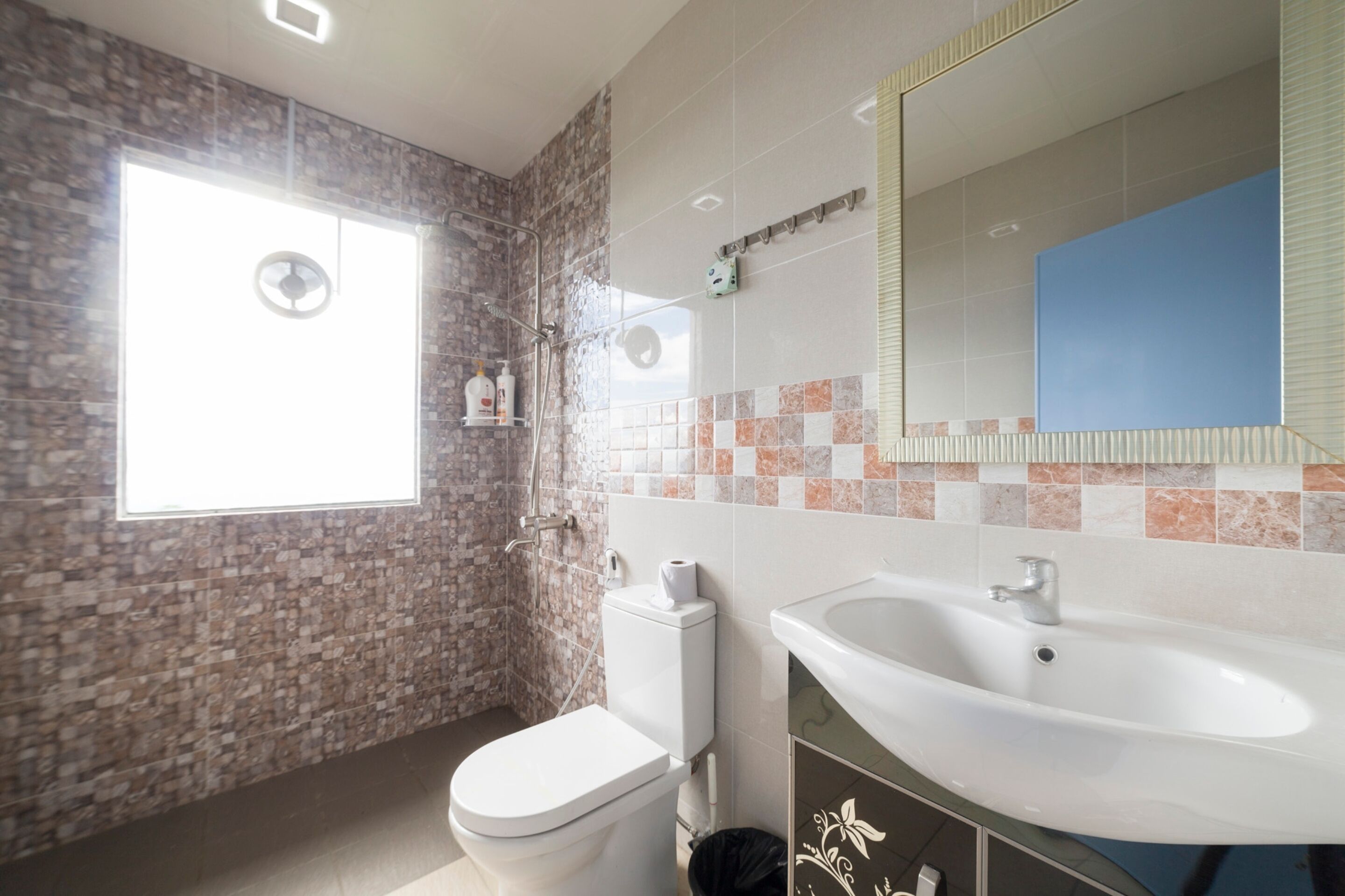 Une salle de bain équipée d’une douche, de toilettes, d’un lavabo et d’un grand miroir.