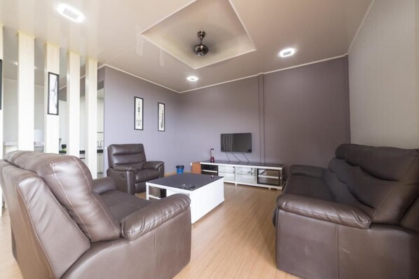 A modern living room with leather sofas, a coffee table, and a flat-screen TV mounted on the wall. - Kokol Heights Villa (Kota Kinabalu)