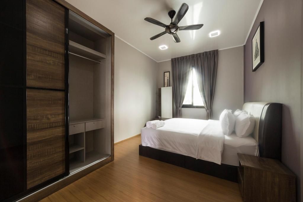 A bedroom with a bed, a ceiling fan, a wardrobe, and a window with curtains.