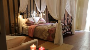 Un dormitorio con una cama con dosel, una mesita de noche y una mesa de vidrio con velas.