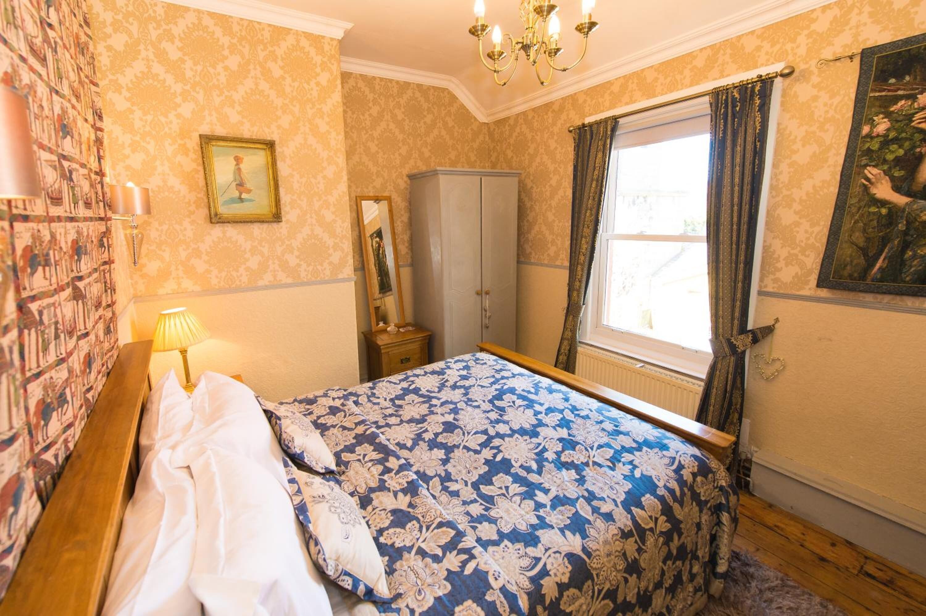 Une chambre à coucher avec un lit, une armoire, un miroir et une fenêtre avec des rideaux.