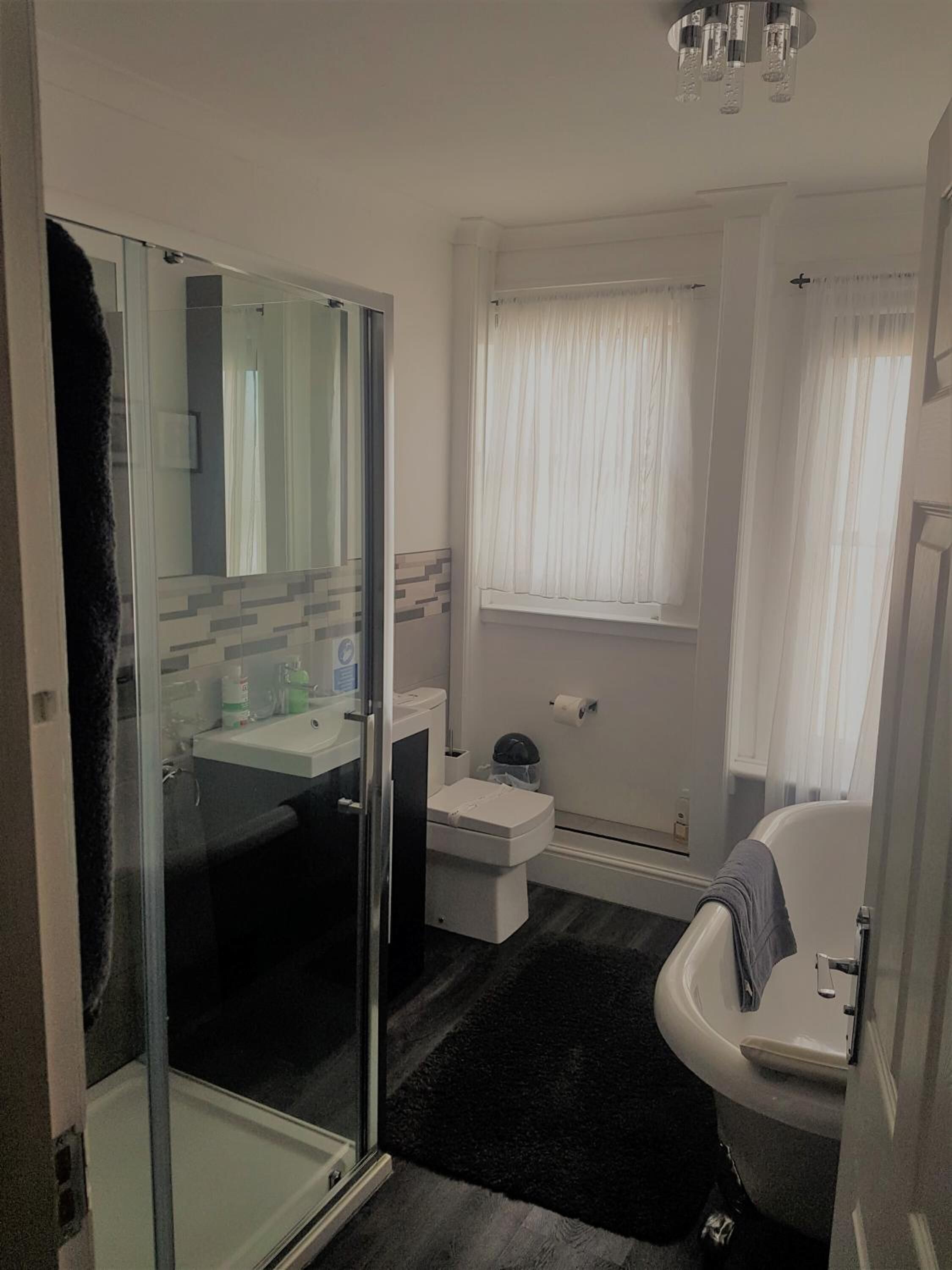 Un baño moderno con cabina de ducha de vidrio, un lavabo blanco, un inodoro y una bañera.