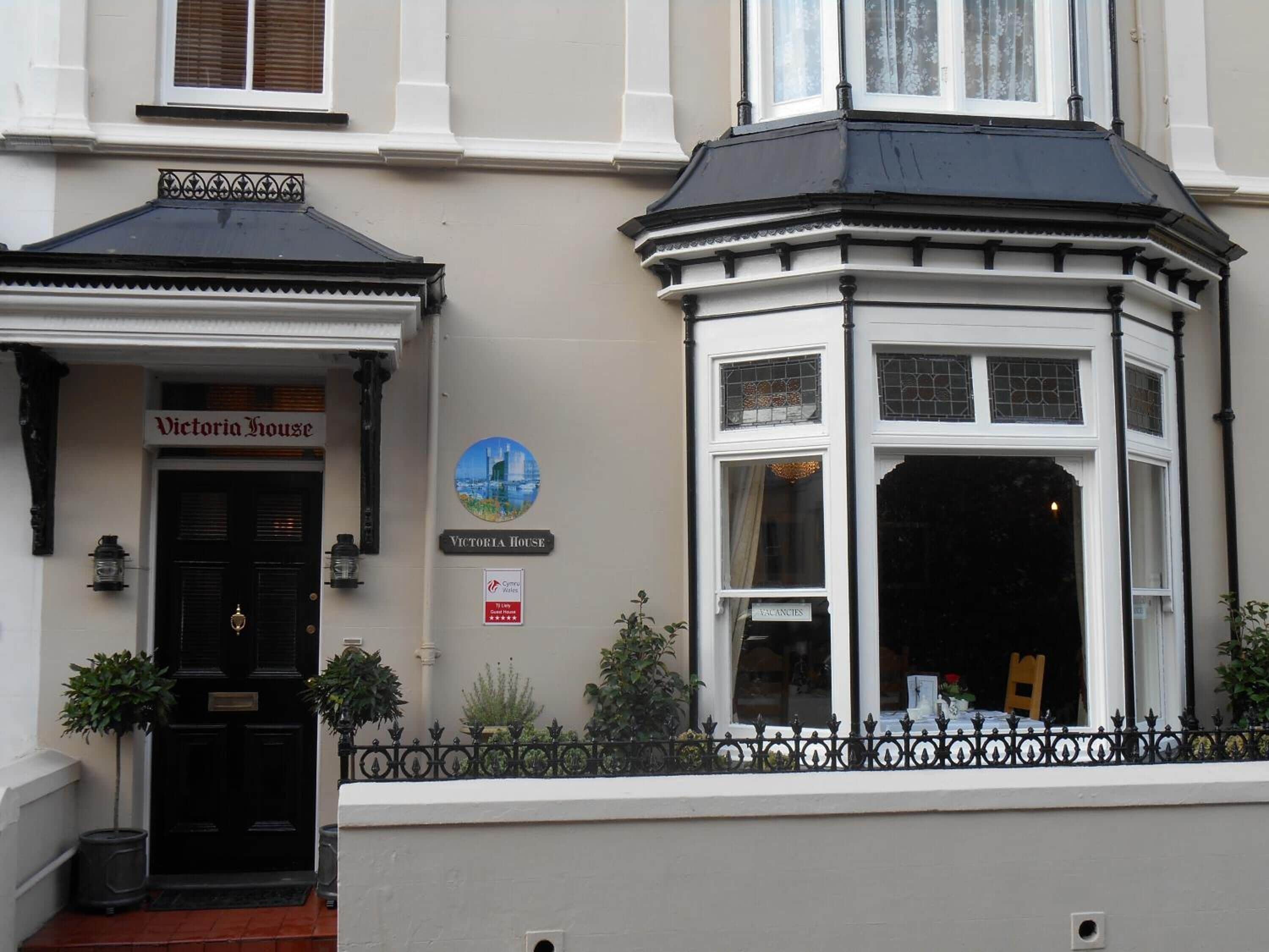 A building with a sign reading "Victoria House" and a "Vacancies" sign.