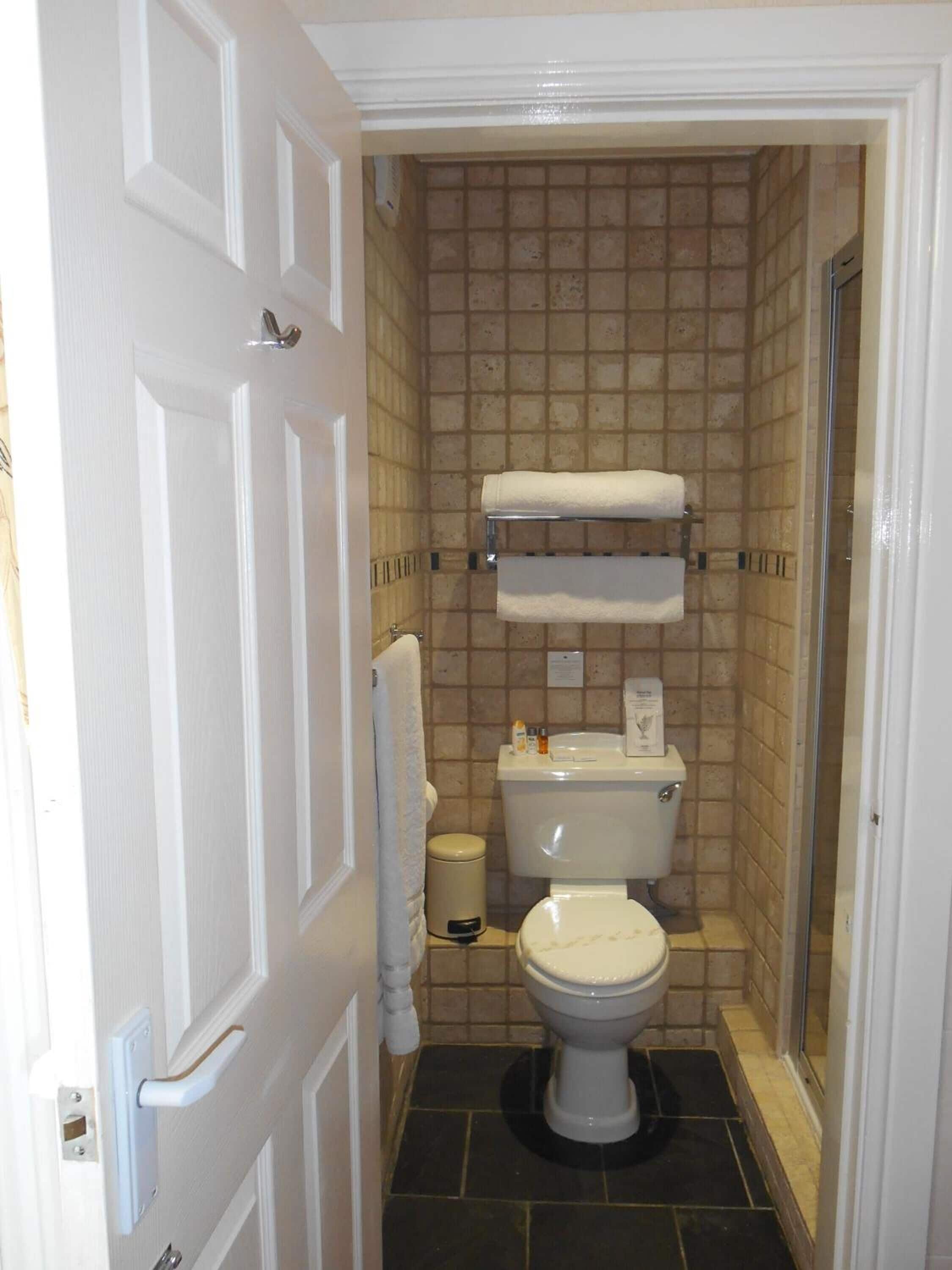 A small bathroom with a toilet, a towel rack, and a trash bin.