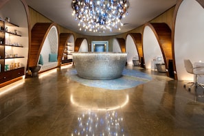 A modern lobby with a central seating area, a chandelier, and a reception desk.