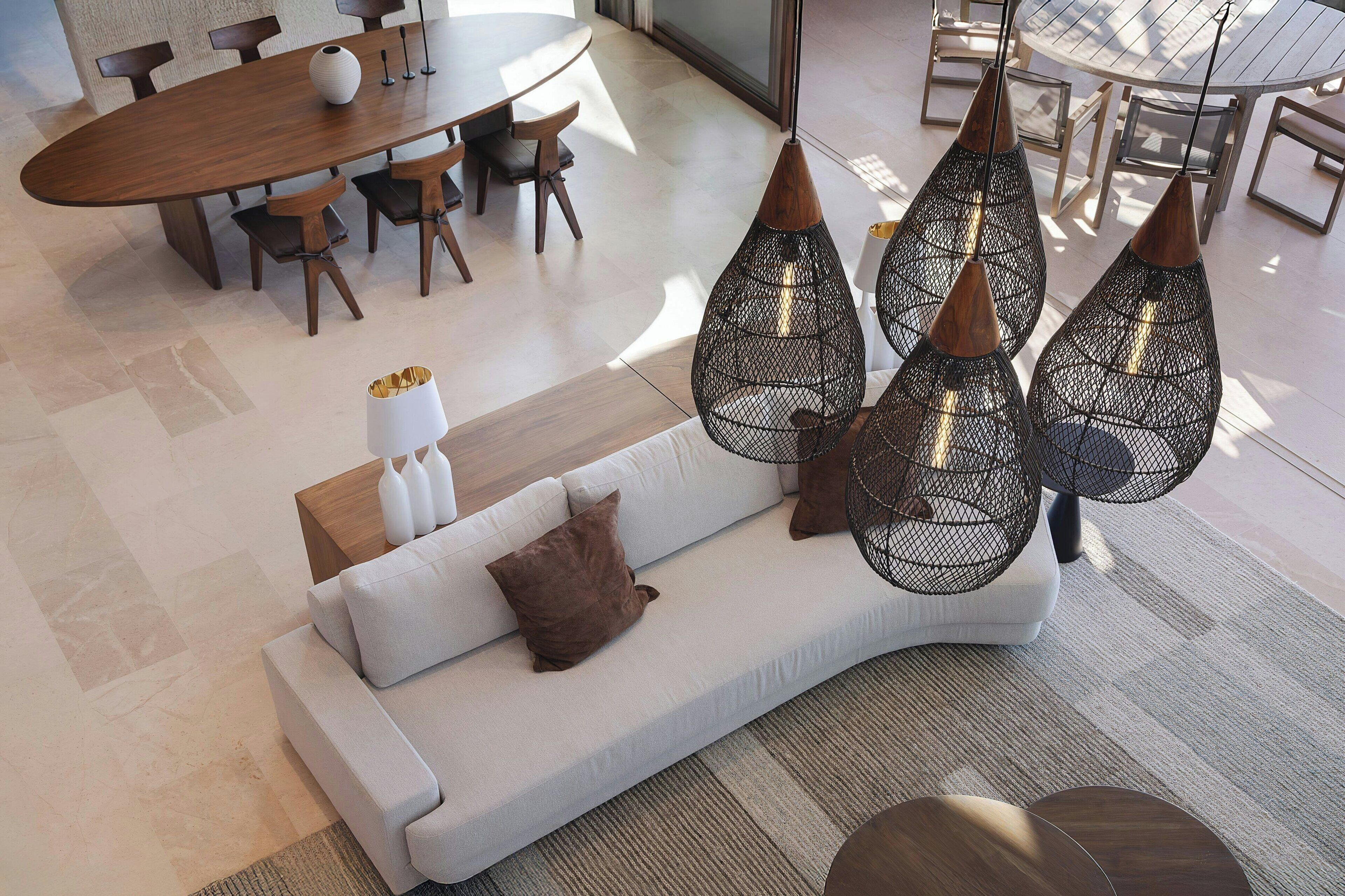 Una sala moderna con sofá, mesa de comedor y lámparas colgantes.