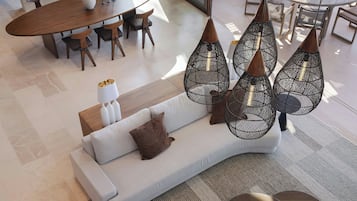 Una sala moderna con sofá, mesa de comedor y lámparas colgantes.