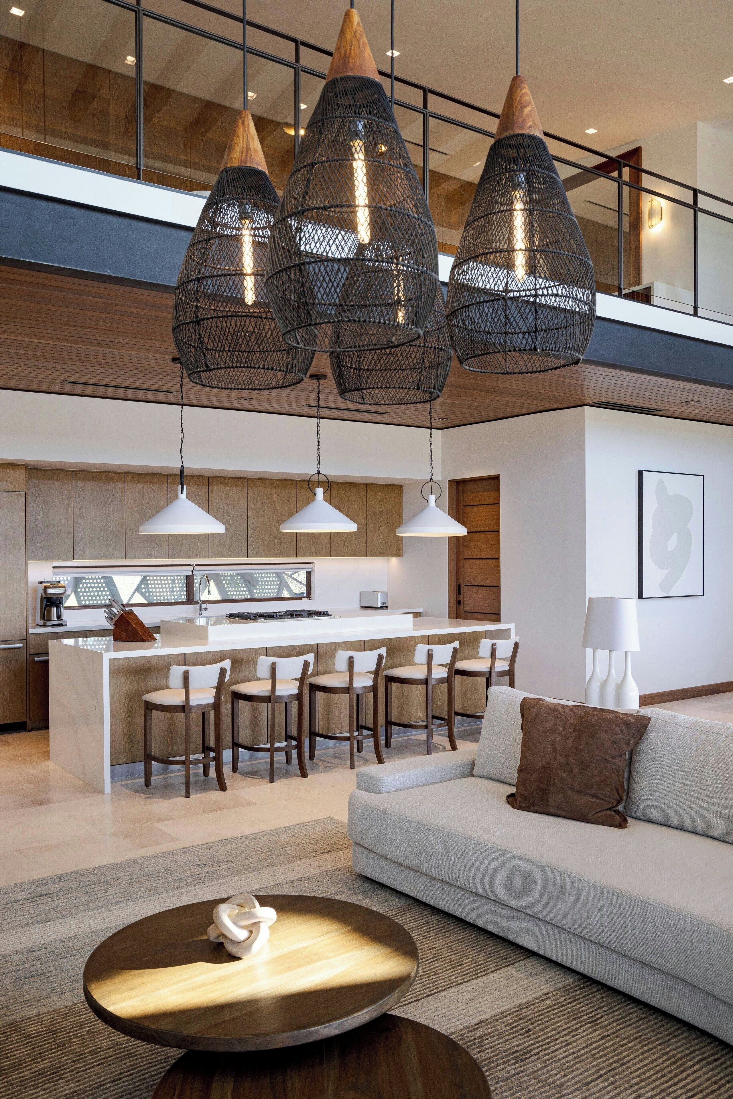 A modern kitchen with a central island, bar stools, and pendant lighting.