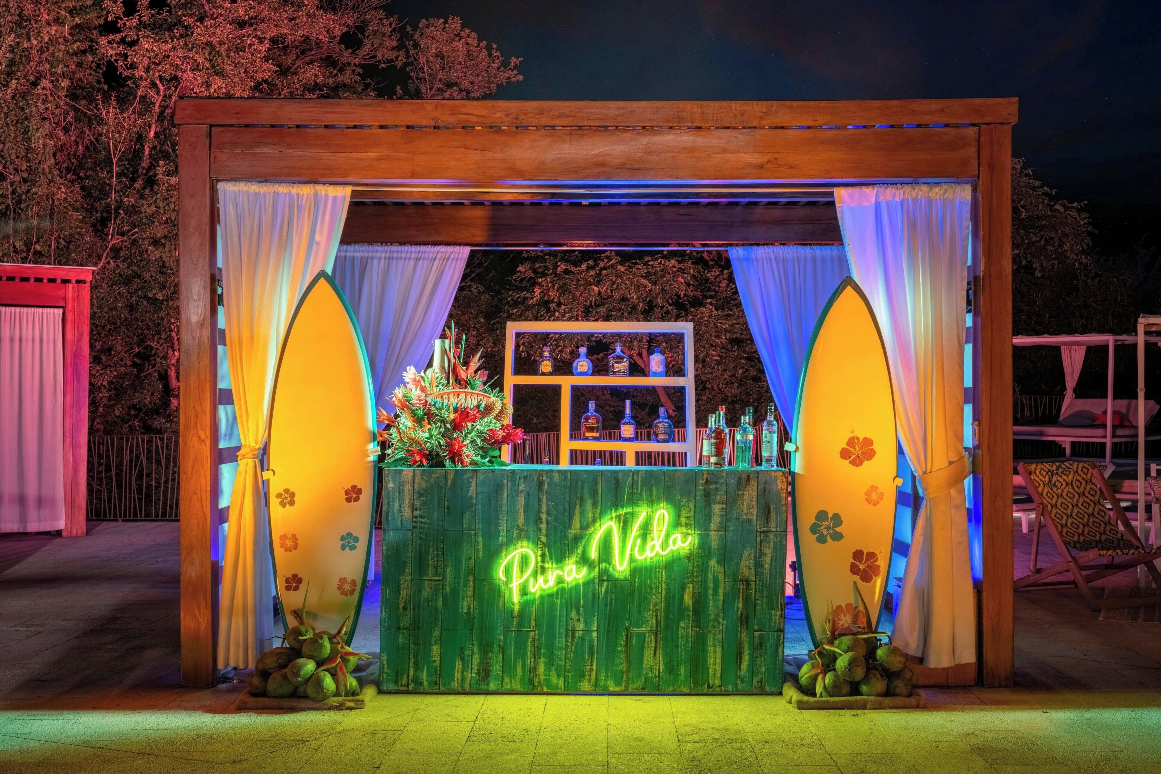 A wooden structure with a neon sign reading 'Pura Vida' and surfboards on either side.