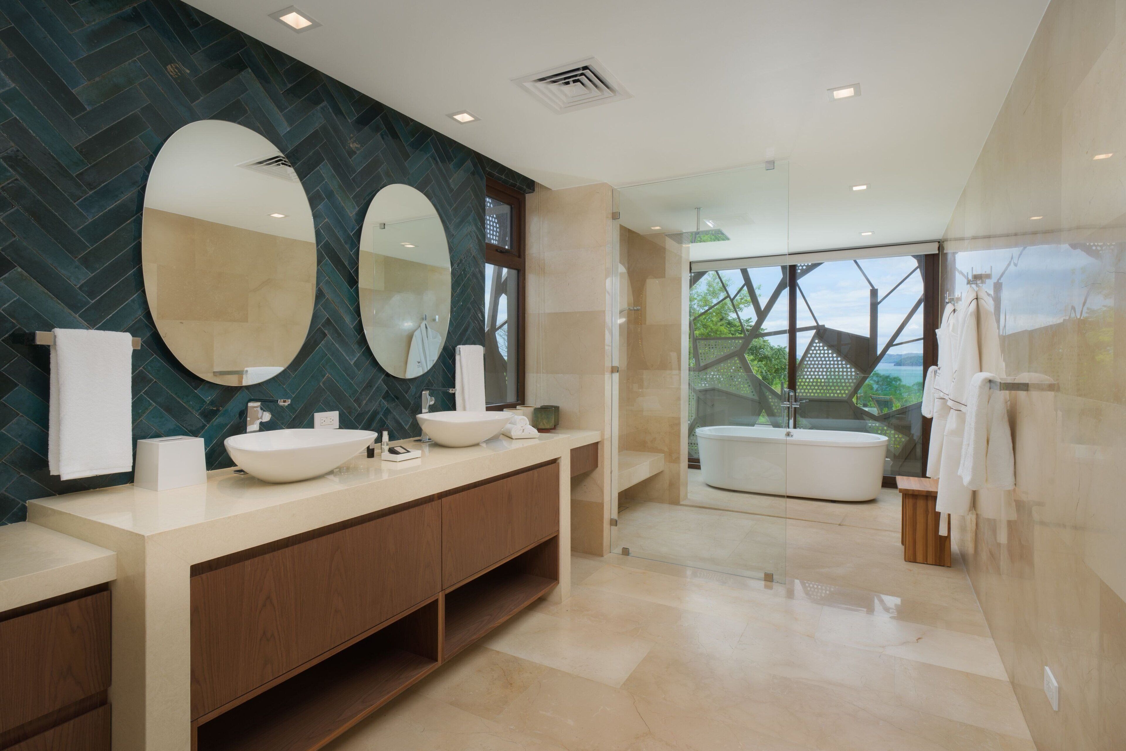 Un baño moderno con un espejo grande, dos lavamanos y una bañera.