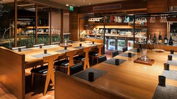 Zona de bar moderna con mobiliario de madera, un expositor de vidrio y una variedad de botellas y copas.