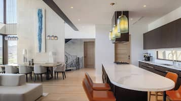 Una cocina moderna con una isla grande, iluminación colgante y un área de comedor con sofá y sillas.