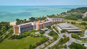 Vista aérea de um hotel com vários edifícios, uma praia e uma grande extensão de água.