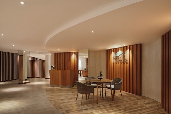 A reception area with a wooden reception desk, wicker chairs, and a wooden floor.