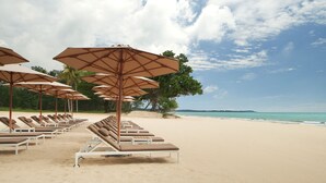 A beach with rows of sun loungers and umbrellas, a sandy shore, and a clear sky. - The Westin Desaru Coast Resort (Bandar Penawar)