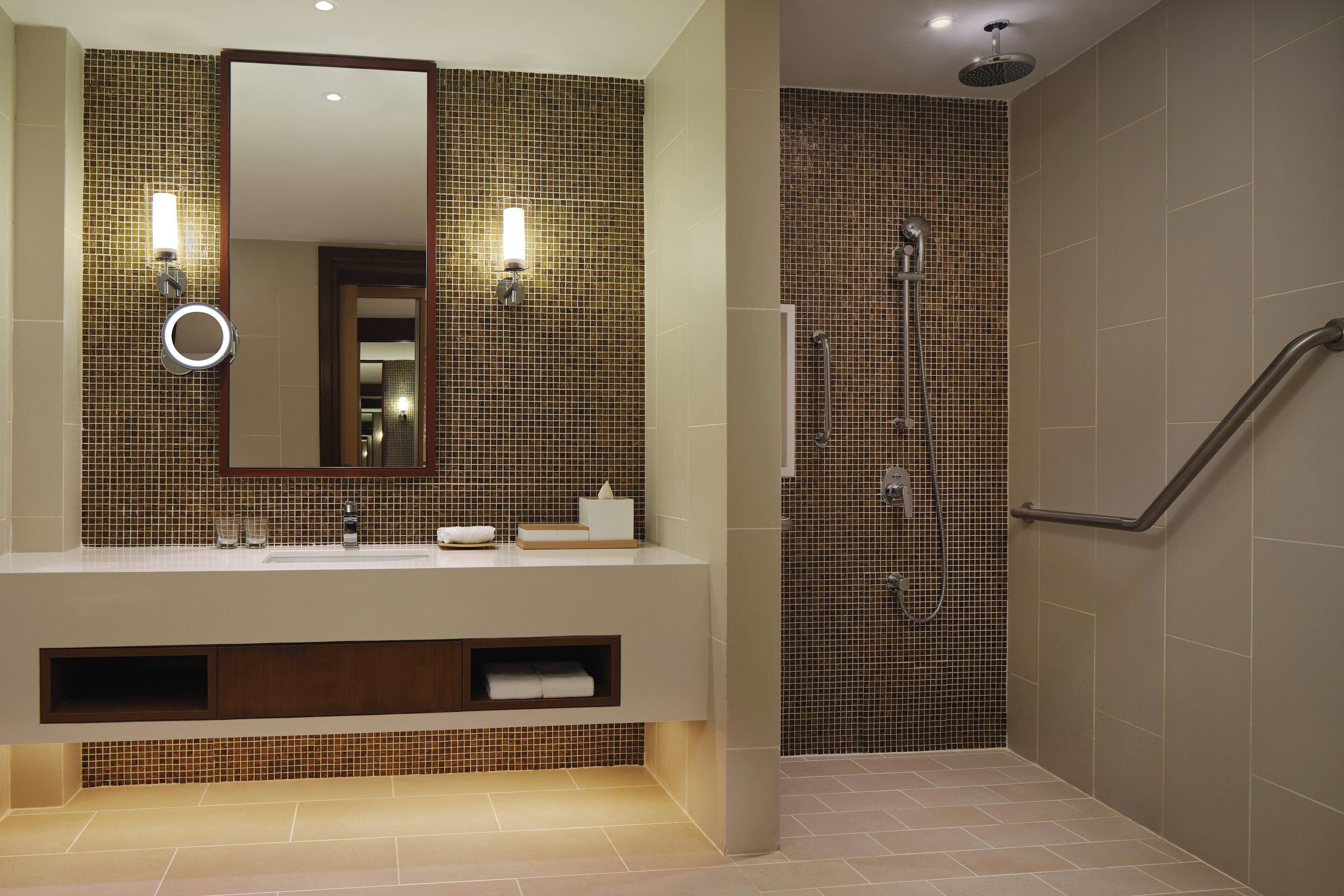 A modern bathroom with a large mirror, a sink, and a shower area.