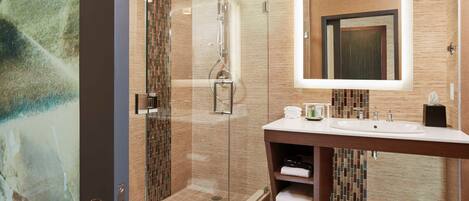 Un baño moderno con cabina de ducha acristalada, un espejo grande y un tocador con lavabo y barra para toallas.