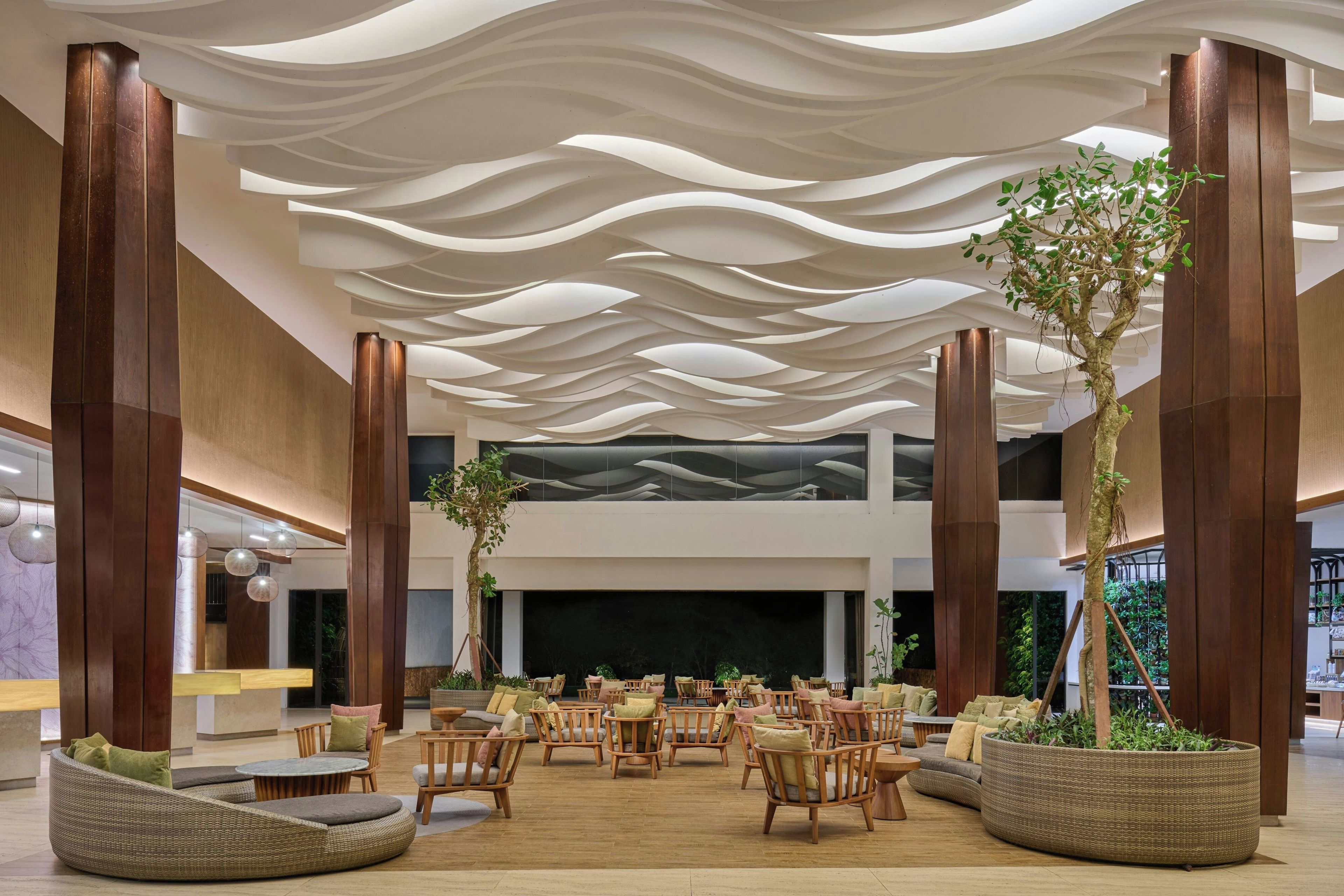 Amplo espaço interno com design de teto moderno, diversos arranjos de assentos e colunas verticais de madeira.